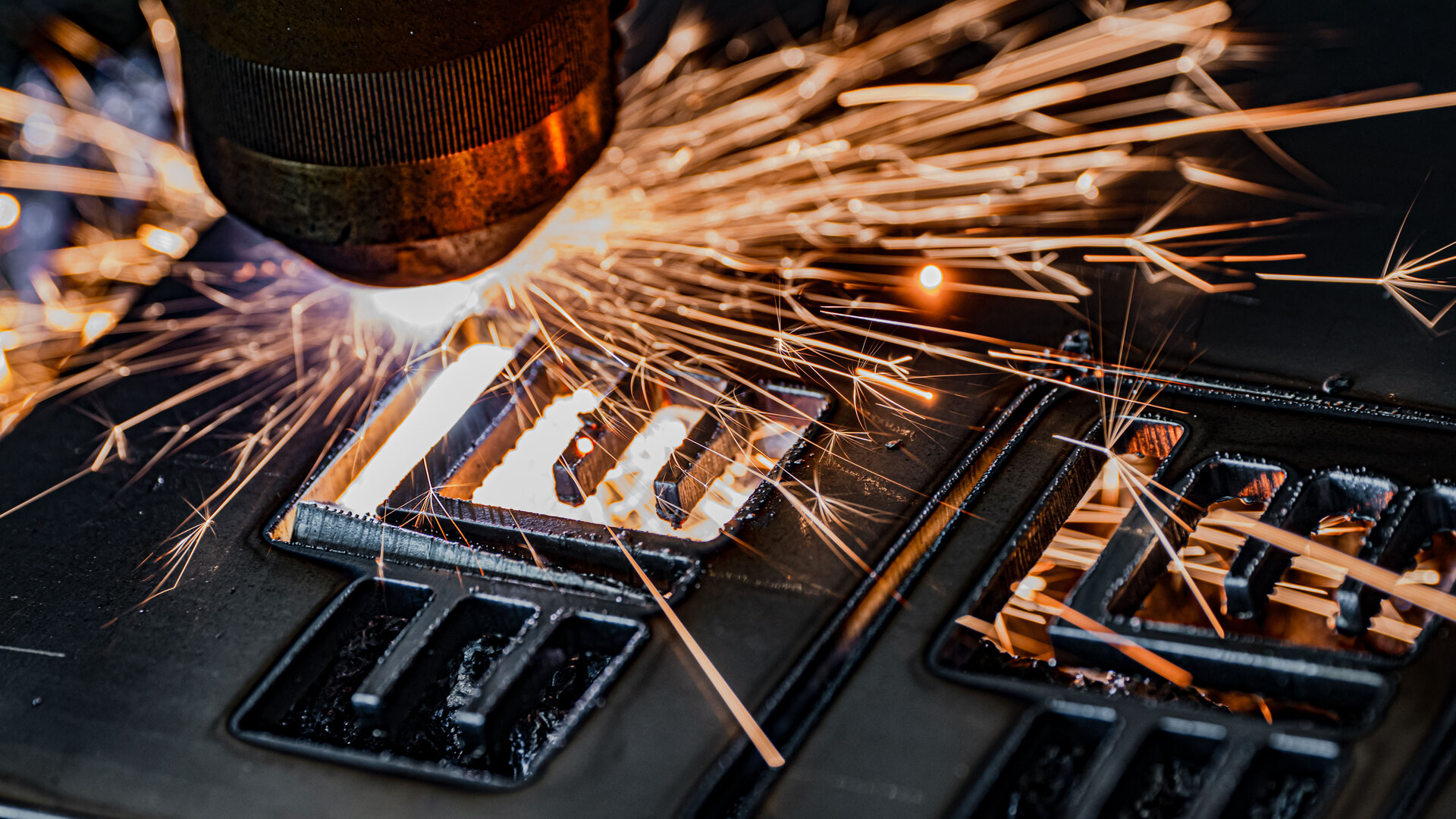 A precise laser beam cuts through metal, while sparks fly in all directions, creating a dynamic scene.